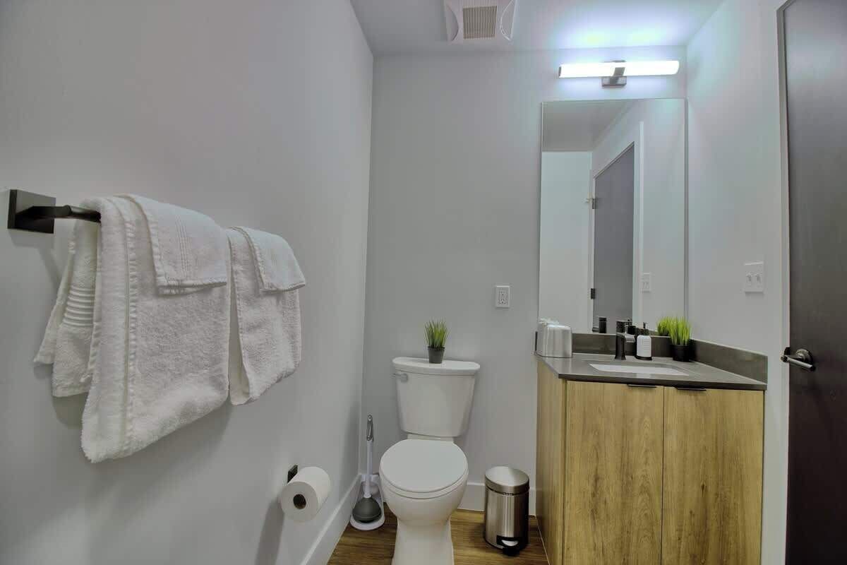 A modern bathroom with a toilet, sink, mirror, and towel rack.