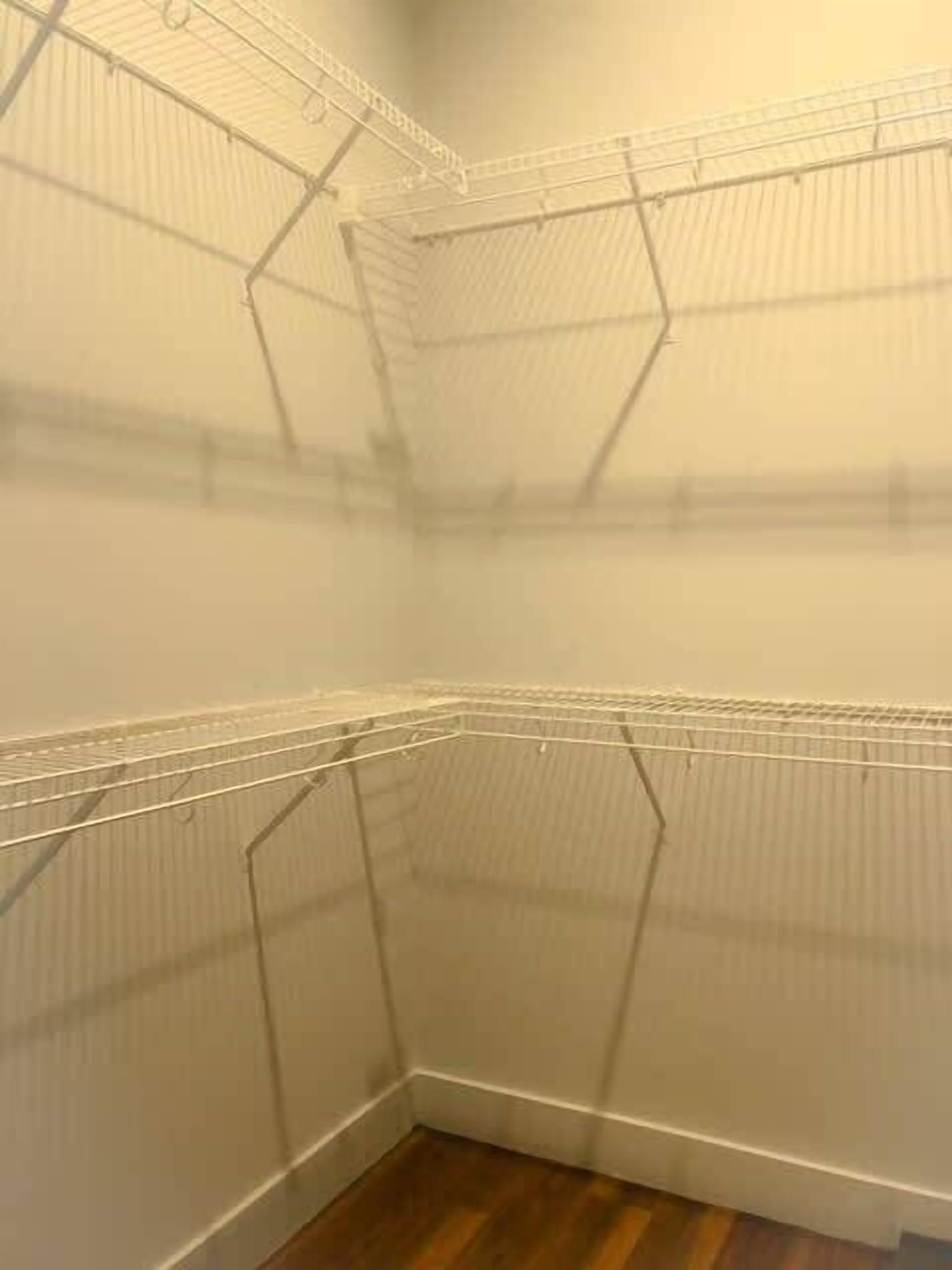 A corner of a room with metal wire shelving units against the walls.