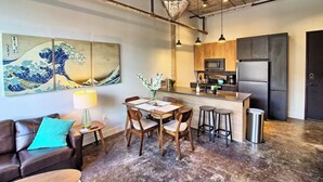 A modern kitchen with a central island, a dining area with a table and chairs, and a living room with a sofa and a coffee table. - Chic Ultramodern Loft w/ Designer Features+WD (Saint Louis)