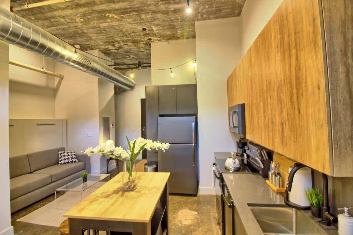 A modern kitchen with stainless steel appliances, a wooden cabinet, and a dining area with a table and chairs.