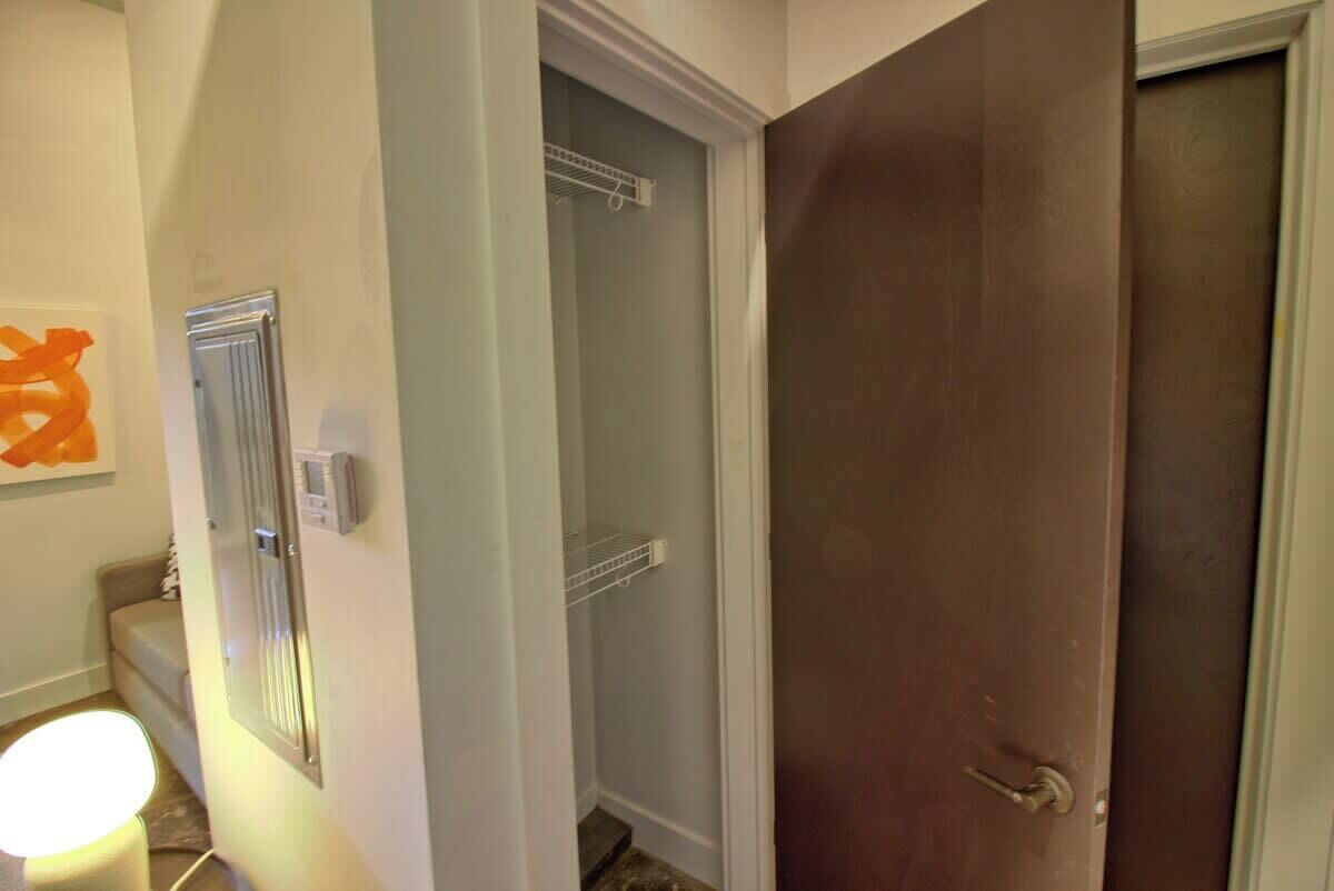 A hallway with a closed door, a light fixture, and a closet with a shelf.