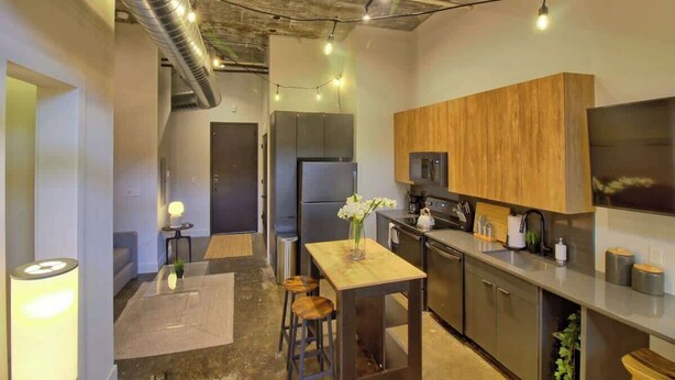 A modern kitchen with stainless steel appliances, wooden cabinets, and a central island. - Chic Ultramodern Minimalist Studio Loft + Patio (Saint Louis)