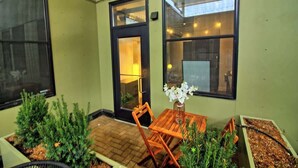 A patio with a wooden table and chairs, a vase with flowers, and potted plants. - Chic Ultramodern Minimalist Studio Loft + Patio (Saint Louis)