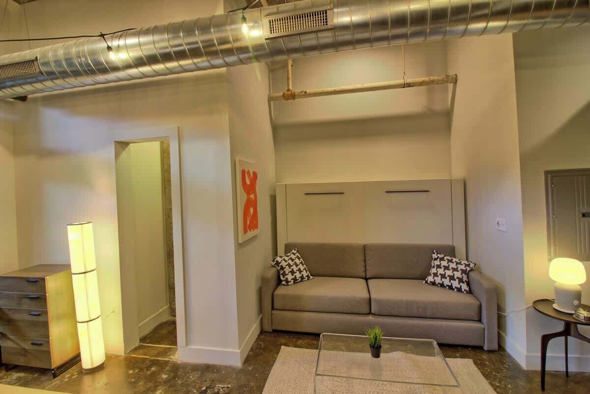 A modern living room with a sofa, a coffee table, a lamp, and a wall-mounted radiator.