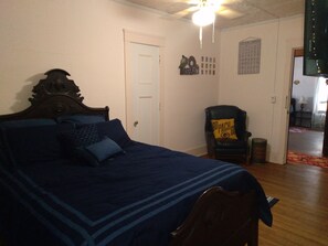 Relax in a spacious bedroom with a large bed, wooden headboard, and comfortable armchair.