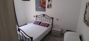 A bedroom with a bed, a nightstand, a wall-mounted shelf, and a door. - The penthouse flat - sea views (L-Isla)