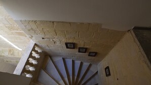 Un escalier en colimaçon, avec un mur en pierre et des tableaux encadrés.