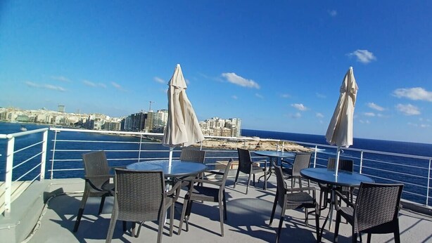 Une terrasse extérieure avec des tables et des chaises, offrant une vue sur le paysage urbain de la côte.