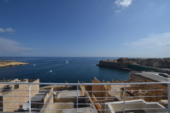 A coastal cityscape with a clear view of the sea and a fortified structure.