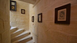 A staircase with stone walls and framed pictures. - 7 La Sengle - Valletta Dream Suites (Il-Belt Valletta)