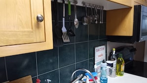Una cocina con armarios de madera, un microondas negro y un letrero que dice 'BACON hace'.
