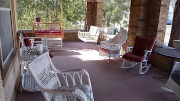 Relax in a serene outdoor space with wicker furniture and a brick wall, offering a view of lush greenery.
