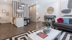 Ein moderner Wohnraum mit Kücheninsel, Barhocker, einer Couch und einem Couchtisch mit Dekoration.