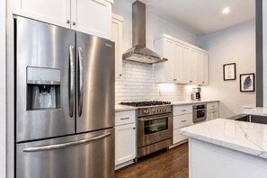 Una cocina moderna con electrodomésticos de acero inoxidable, armarios blancos y un dispensador de agua.