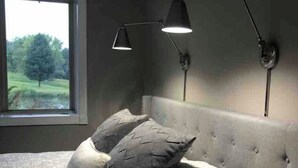 Ein Schlafzimmer mit einem Bett, zwei Kissen, einem Fenster und zwei Wandleuchten.