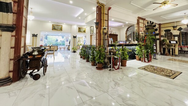 A spacious lobby with marble flooring, a reception desk, potted plants, and a wheelchair. - Tas Saray Bardakci Hotel (Kahta)