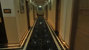 A long, narrow hallway with a black marble floor and white trim, leading to a door with a brick pattern. - Tas Saray Bardakci Hotel (Kahta)