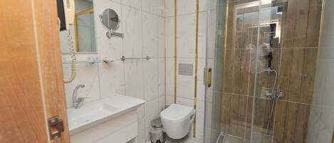 A modern bathroom with a glass-enclosed shower, a white sink, and a toilet.