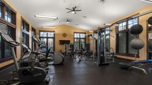 Un gimnasio con cintas de correr, máquinas de pesas y un ventilador de techo.