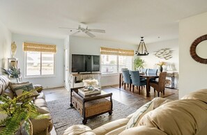 Un salon spacieux avec un canapé, une table basse et un téléviseur. Il y a également un coin repas avec des chaises et une table.
