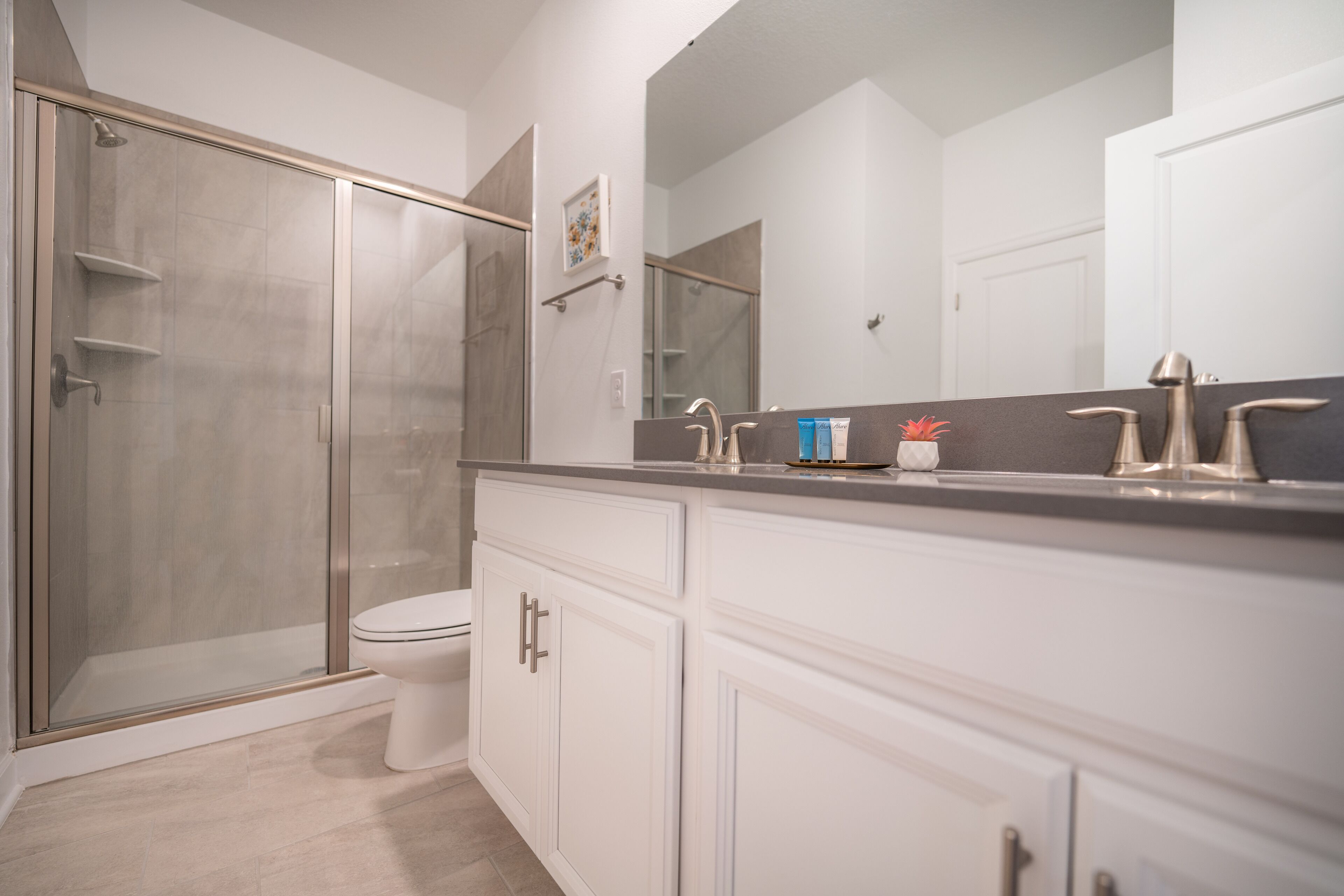 Un baño moderno con cabina de ducha, inodoro y tocador con un espejo grande.