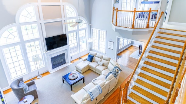 A spacious living room with a large sectional sofa, a fireplace, and a staircase leading to an upper level.