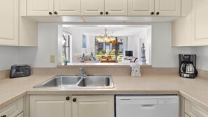 A kitchen with white cabinets, a double sink, and a dishwasher.