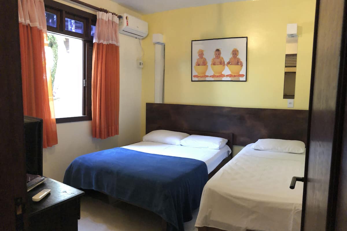 A hotel room with two beds, a TV, and a painting on the wall.