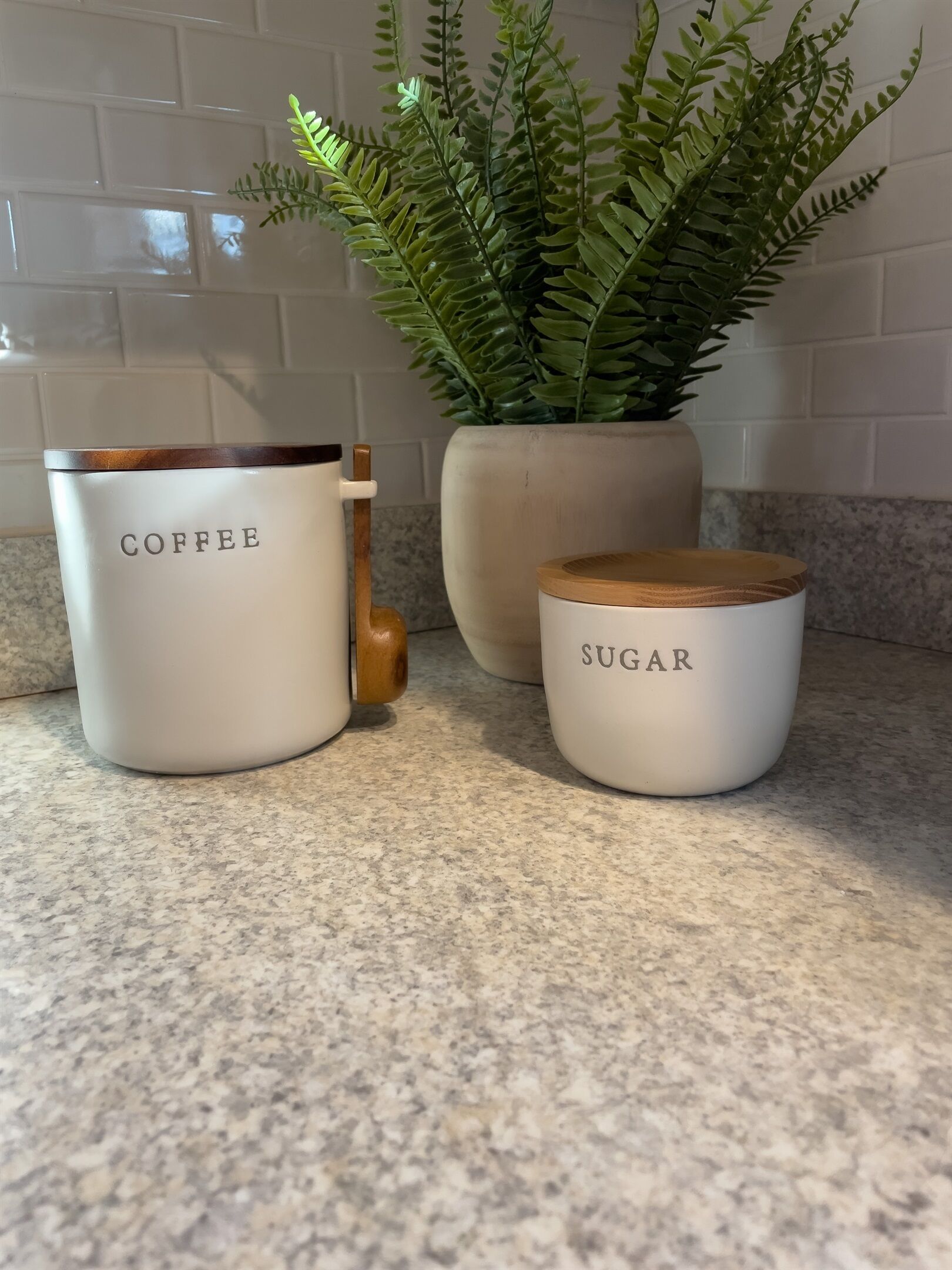 Three white containers with labels on a kitchen counter.