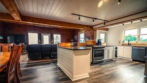 A spacious kitchen with wooden floors, a central island, and white cabinetry. - SUMMER SPECIALS  Beautiful lake front, beach and pool table (LaPointe)