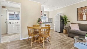 A modern living room with a dining area, a grey sofa, and a kitchen in the background.