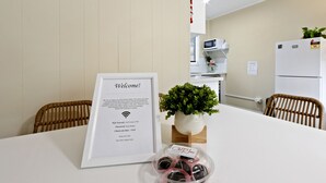 Un espace d’accueil agrémenté d’une pancarte de bienvenue encadrée, d’une petite plante et d’une table sur laquelle se trouve une boîte en plastique remplie de chocolats.