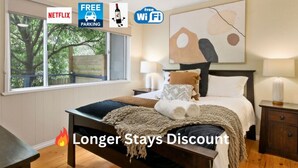 Une chambre à coucher avec un lit, des tables de chevet, une fenêtre et un ventilateur de plafond.