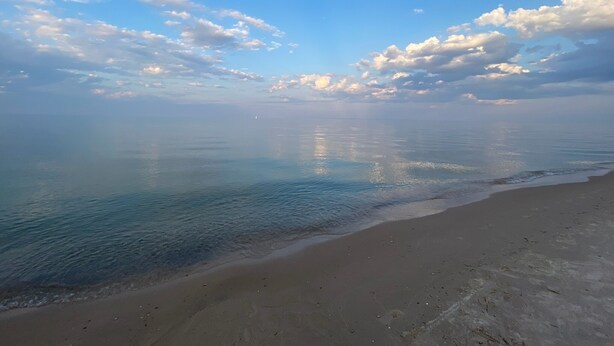 Une plage avec une eau calme et un ciel dégagé.