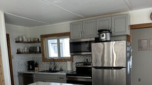 Een moderne keuken met een marmeren aanrecht, roestvrijstalen apparatuur en gele barkrukken.