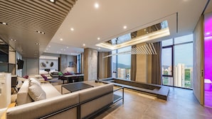 Una sala de estar moderna con sofá, comedor y ventanas amplias con vistas a la ciudad.