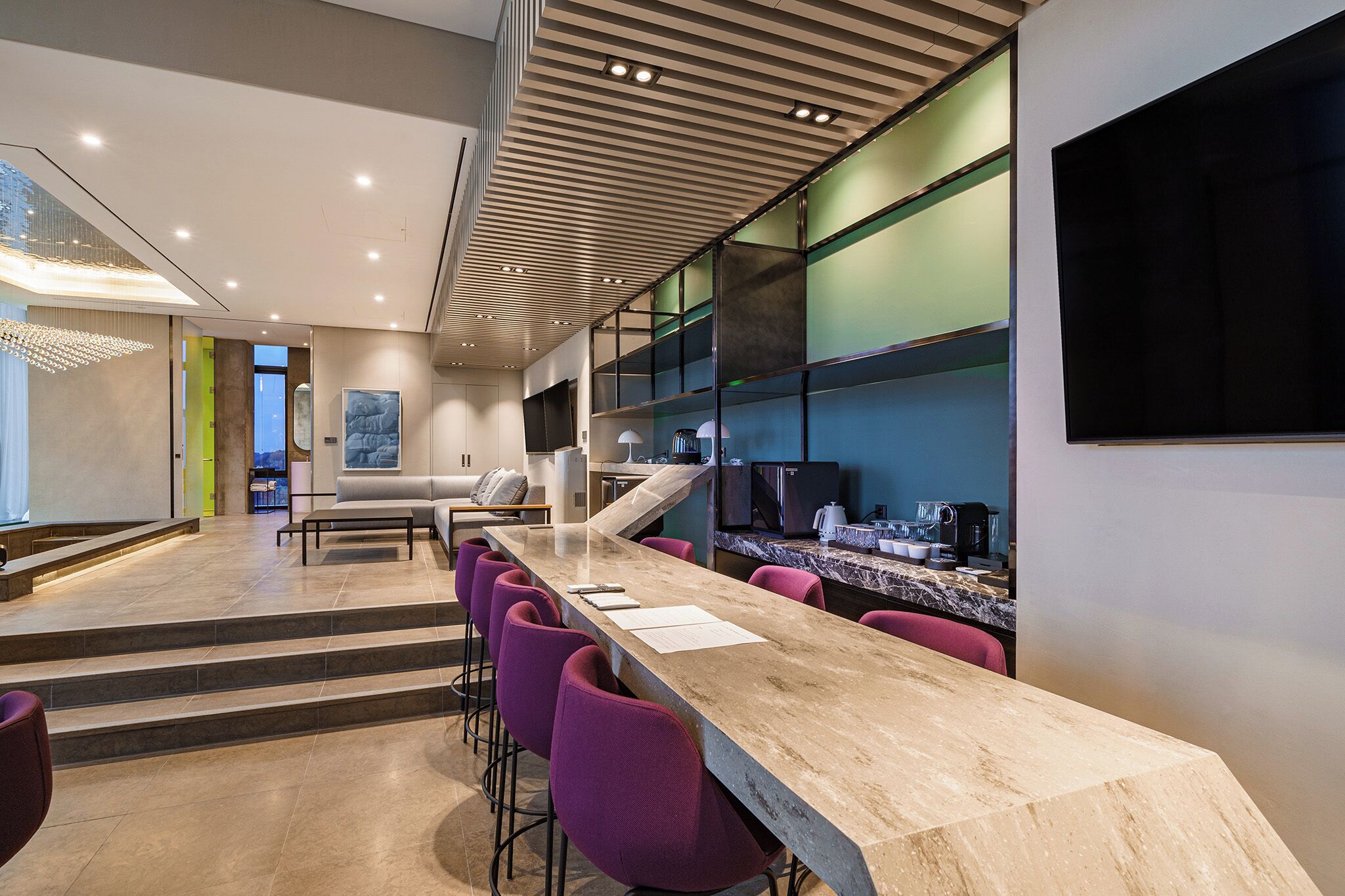 Una cocina moderna con una isla grande, taburetes de bar y un televisor de pantalla plana.