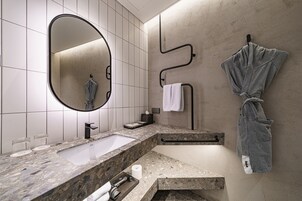 A modern bathroom with a large mirror, a sink, and a towel rack.