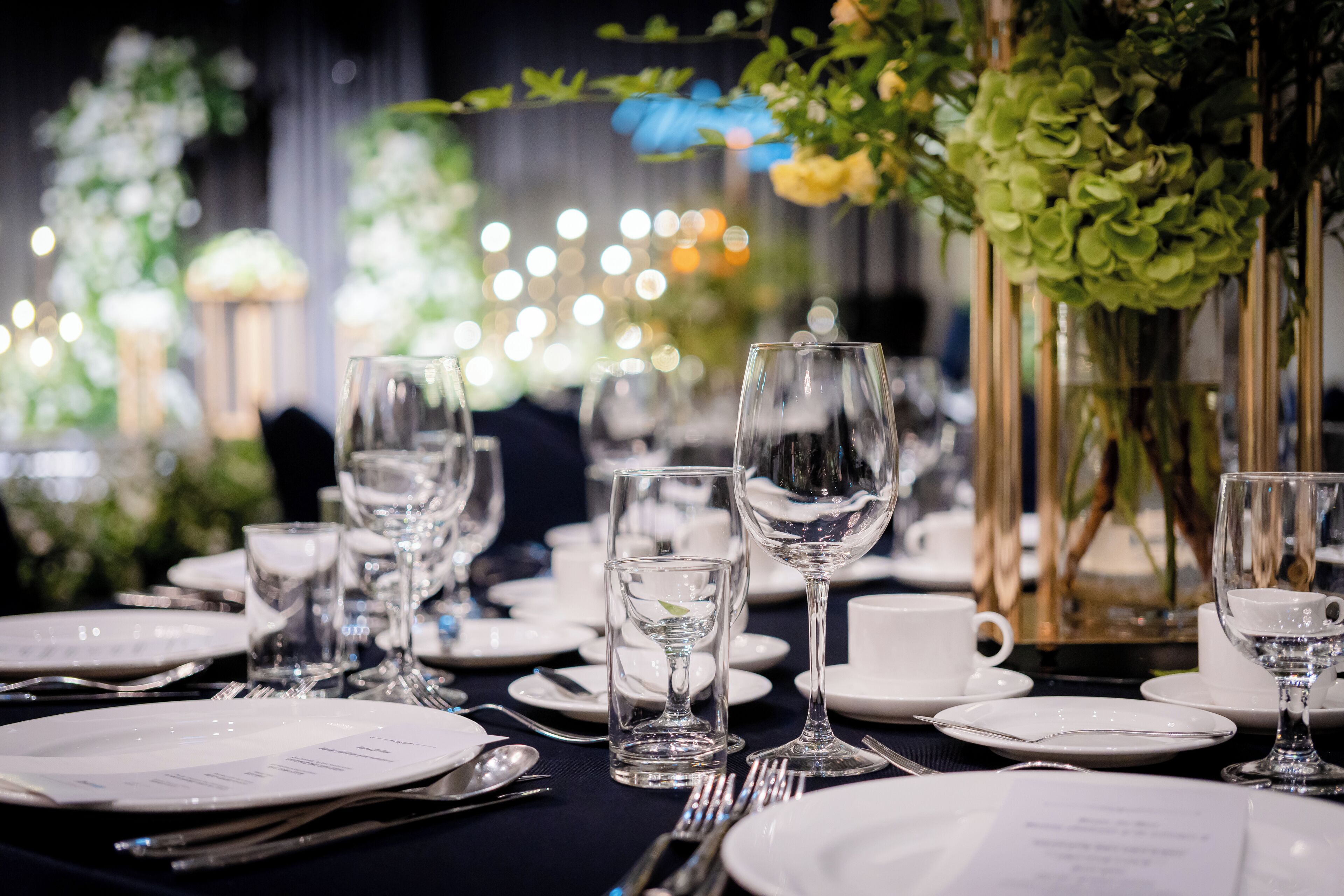 A table set for a formal dining event with clear glassware, plates, and cutlery.