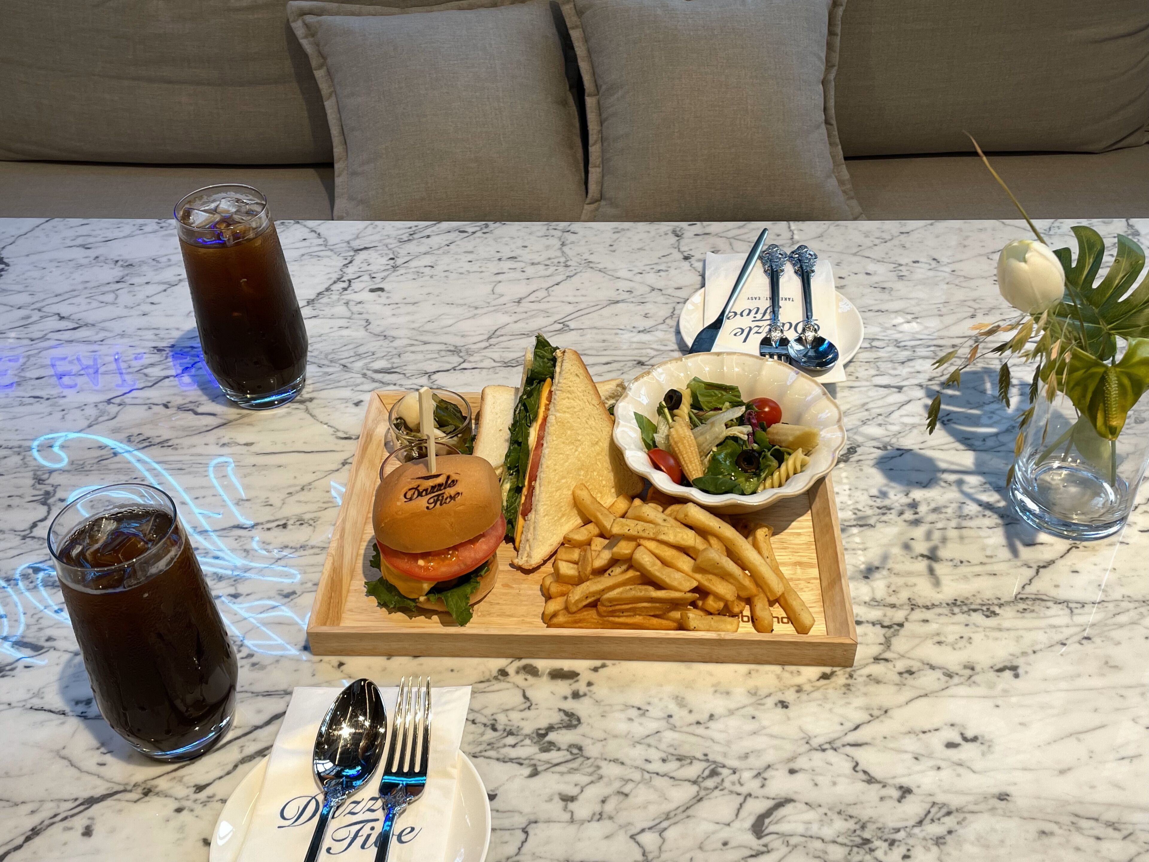 A dining table with a burger, fries, salad, and drinks.