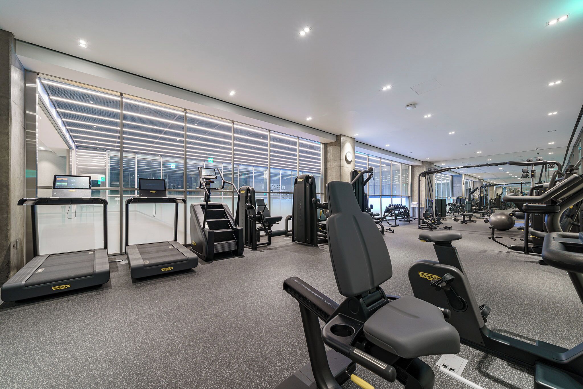 Une salle de sport moderne équipée de tapis de course, de vélos elliptiques et de matériel de musculation.