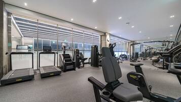 A modern gym with treadmills, elliptical machines, and weight equipment.