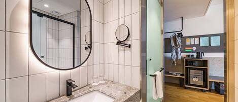 Un baño moderno con un espejo grande, un lavabo y una cabina de ducha de vidrio.