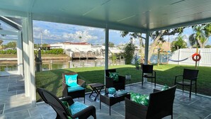 An outdoor patio with wicker furniture and a view of a marina. - LILY'S BEACH HOUSE - POOL HOUSE WITH DIRECT RIVER ACCESS (Cape Coral)