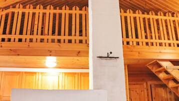 Un intérieur en bois avec un plafond haut, un pilier blanc et un escalier en bois.