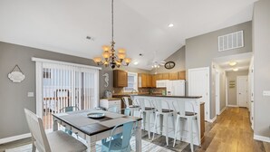 A modern kitchen with a central island, white cabinetry, and a chandelier.