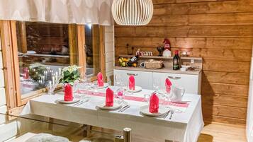 A dining area with a wooden interior, a table set for four with pink napkins, and a hanging light fixture above.