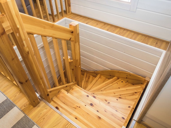 Una silla de madera con estructura metálica, suelo de madera y pared blanca con líneas horizontales.