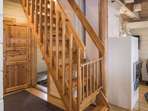 A wooden staircase with a railing, a wooden door, and a white refrigerator in a room. - Pähkinä by Interhome (Kuusamo)