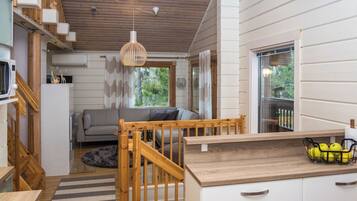 A modern kitchen with wooden accents, a dining area with a sofa, and a view of greenery outside.